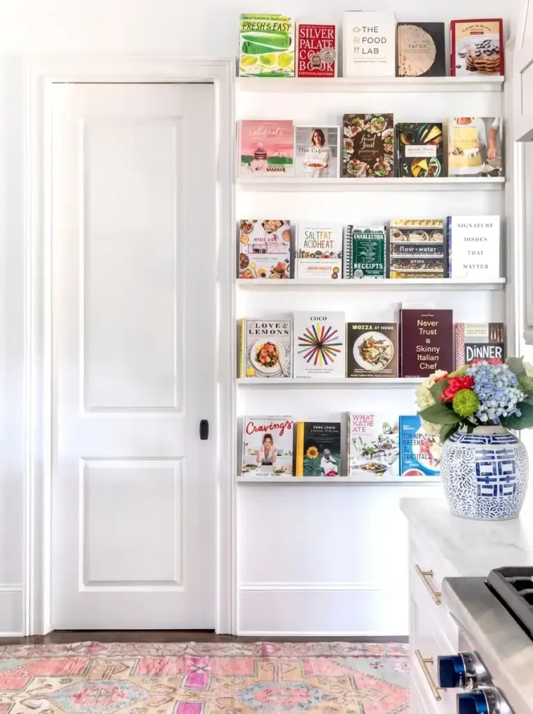 Ledge shelves in a modern kitchen filled with colorful hardback cookbooks.