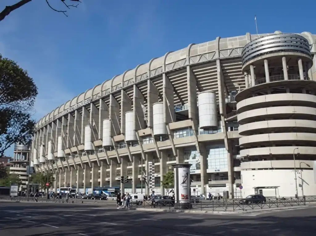 Exterior view of the Santiago Bernabéu stadium in Madrid under evening floodlights.